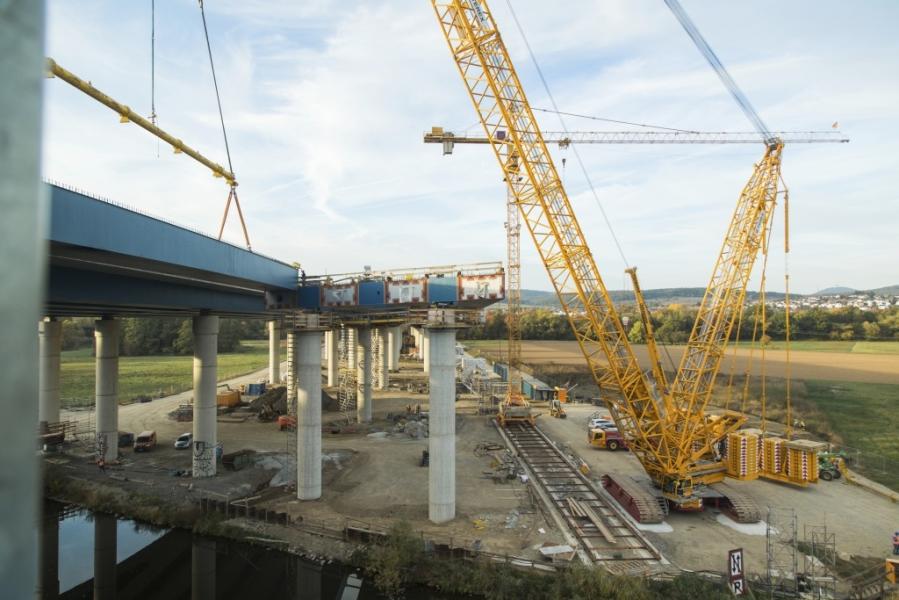 Demag CC 3800-1 lattice boom crawler crane lifts bridge components at freeway work site